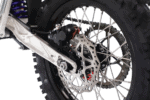 Close-up of a motocross bike's rear wheel, disc brake, and suspension system, showcasing high-performance racing components.