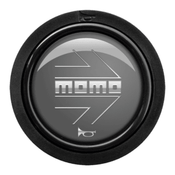 Close-up of a MoMo racing wheel logo on a black steering wheel rim, highlighting motorsport branding.