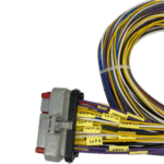 Close-up of a wiring harness with multicoloured wires and a white connector, used in racewear electronics for Grand Prix racing.