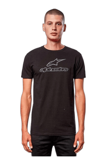 Young woman wearing black Alpinestars T-shirt, standing confidently, showcasing racing apparel for motorsport enthusiasts.