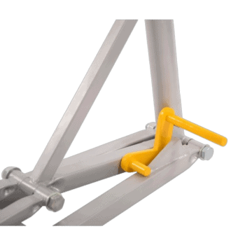 Close-up of a metal racing simulator pedal with a yellow brake pedal and grey frame, used for motorsport gaming and training.