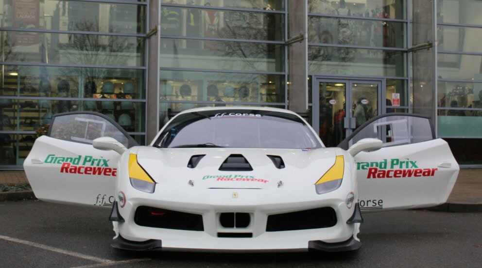 High-performance race car with open doors at Grand Prix Racewear event, showcasing sleek design and branding.