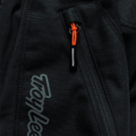 Close-up of Troy Lee Designs SCOUT GP PRO Mono Bottoms with black fabric and orange zipper pull, highlighting durable motocross gear features.