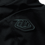 Close-up of Troy Lee Designs logo on black racewear fabric, highlighting high-quality motocross gear.