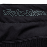 Close-up of Troy Lee Designs logo on black racewear fabric, highlighting premium motocross gear quality.